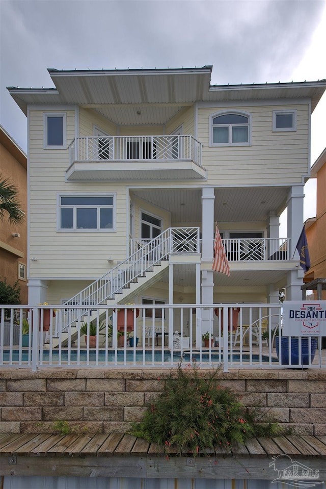 back of house featuring stairs, fence, and a balcony