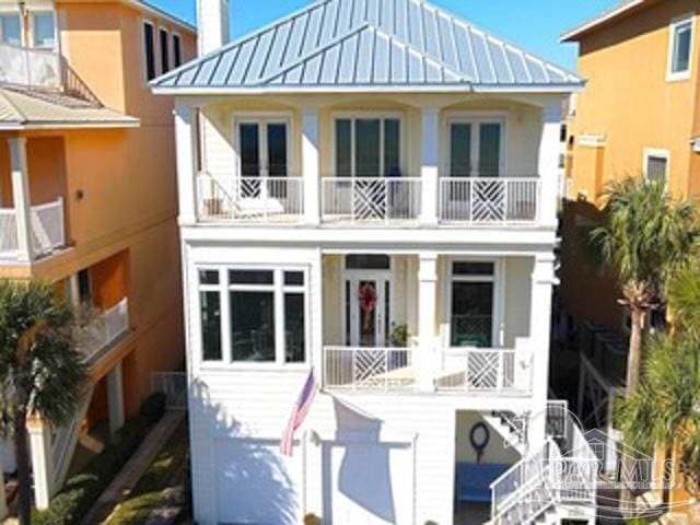 coastal inspired home featuring metal roof, a chimney, and a balcony