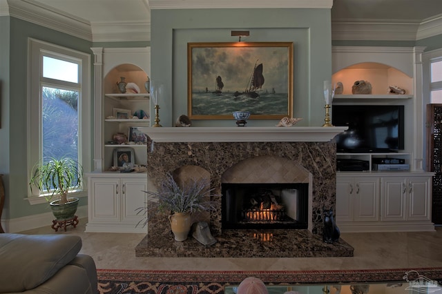 sitting room with built in shelves, crown molding, and a premium fireplace