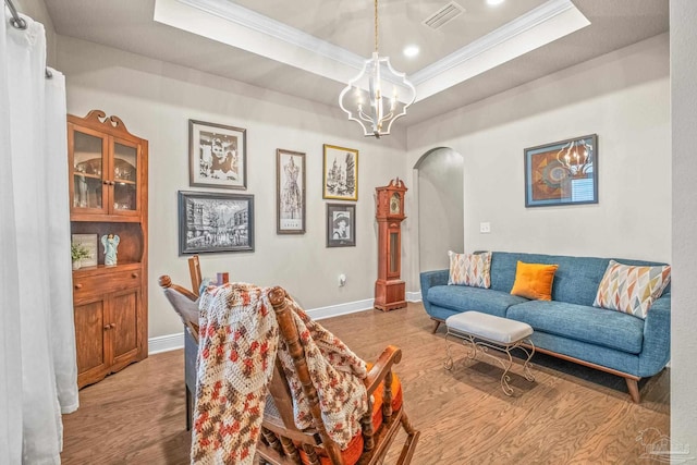 living area with arched walkways, a chandelier, visible vents, a raised ceiling, and crown molding