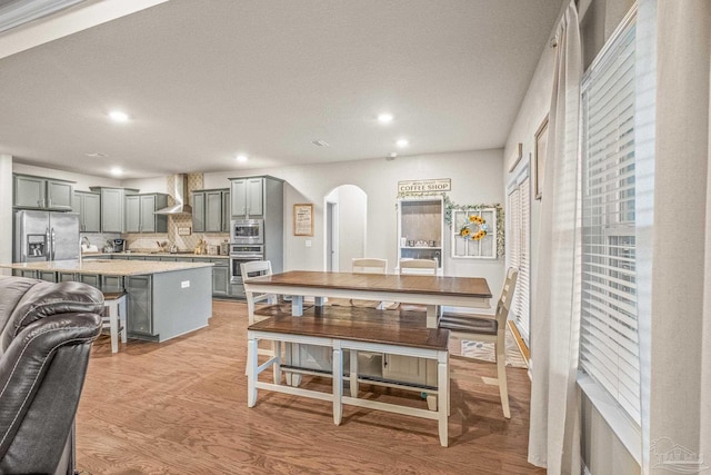 dining area with light wood-type flooring, arched walkways, and recessed lighting