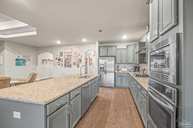 kitchen featuring stainless steel appliances, light wood-type flooring, gray cabinets, and a sink