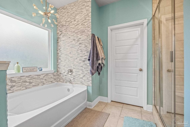 bathroom featuring a garden tub, a shower stall, a chandelier, and tile patterned floors