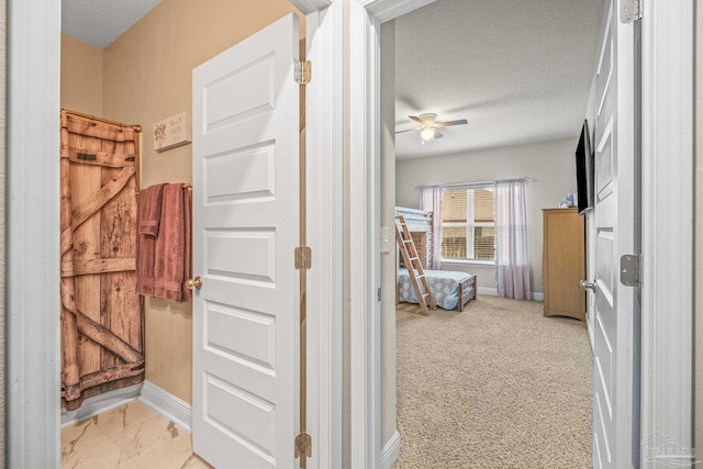 hallway with light carpet, a textured ceiling, and baseboards