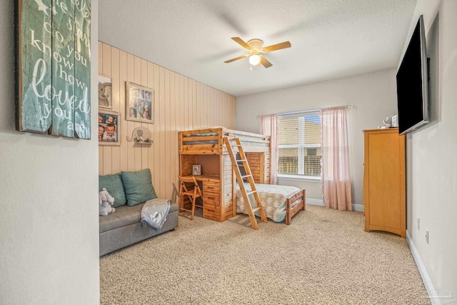 carpeted bedroom with wood walls, baseboards, a ceiling fan, and a textured ceiling