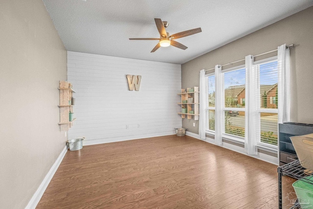 unfurnished room featuring a textured ceiling, wood finished floors, a ceiling fan, and baseboards