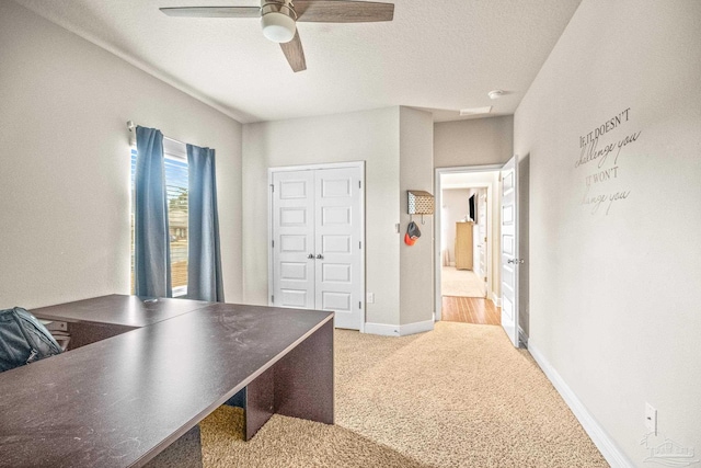 carpeted office featuring ceiling fan, a textured ceiling, and baseboards