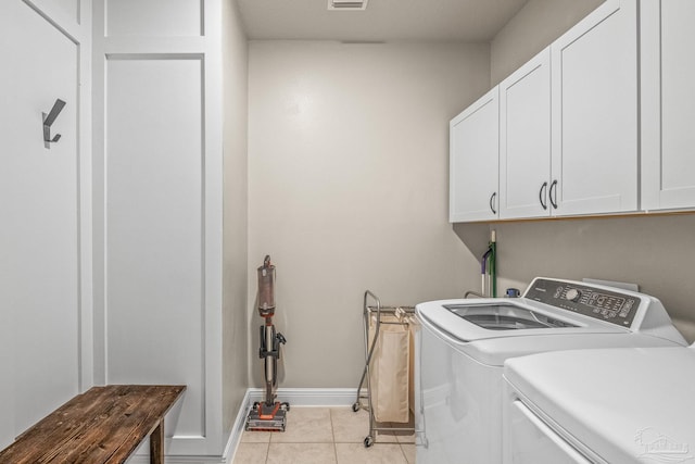 laundry area featuring light tile patterned floors, washing machine and dryer, cabinet space, and baseboards