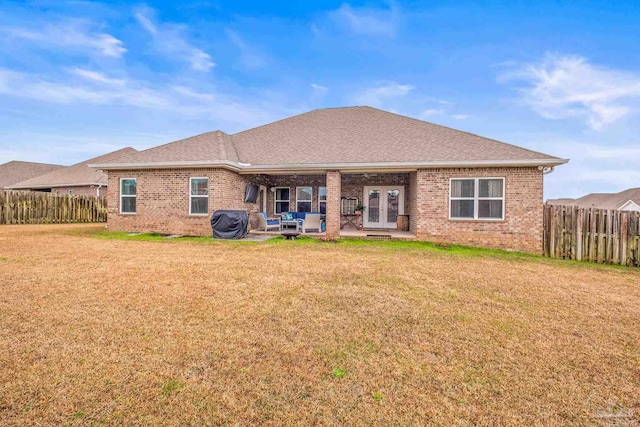 back of property with a yard, french doors, fence, and brick siding