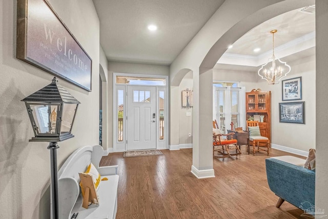 entryway featuring a wealth of natural light, arched walkways, baseboards, and wood finished floors