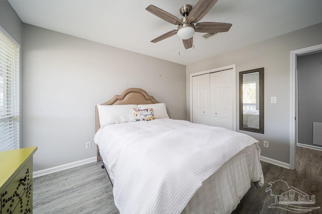 bedroom featuring baseboards, visible vents, a closet, and wood finished floors