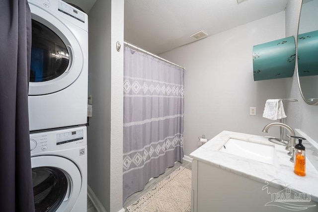 clothes washing area with stacked washer and dryer, a sink, and visible vents