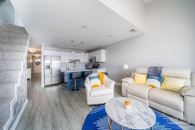 living area featuring visible vents, baseboards, light wood-style flooring, and recessed lighting