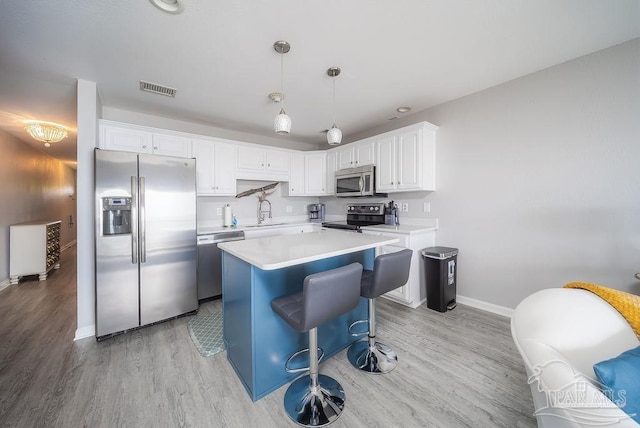 kitchen featuring visible vents, appliances with stainless steel finishes, light countertops, light wood-type flooring, and a sink