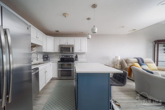 kitchen with stainless steel appliances, light countertops, visible vents, open floor plan, and a sink