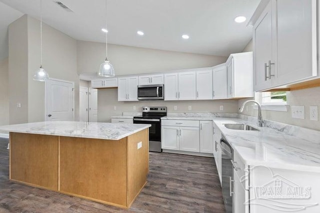 kitchen with appliances with stainless steel finishes, white cabinetry, a kitchen island, and sink