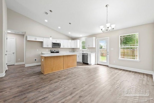 kitchen with hardwood / wood-style floors, a center island, decorative light fixtures, white cabinetry, and stainless steel appliances