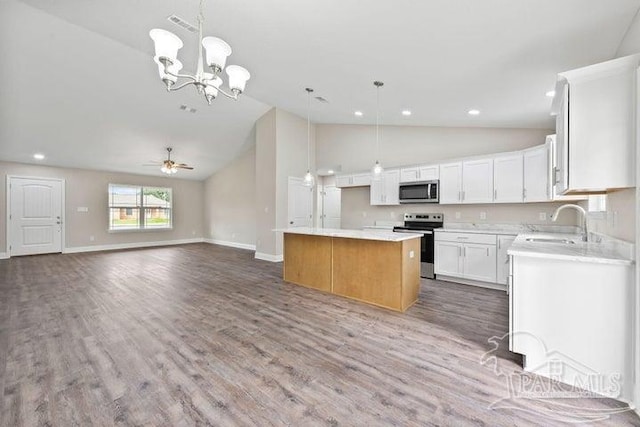 kitchen featuring pendant lighting, white cabinets, ceiling fan with notable chandelier, appliances with stainless steel finishes, and a kitchen island