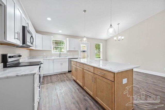 kitchen featuring appliances with stainless steel finishes, light stone counters, white cabinets, a center island, and hanging light fixtures