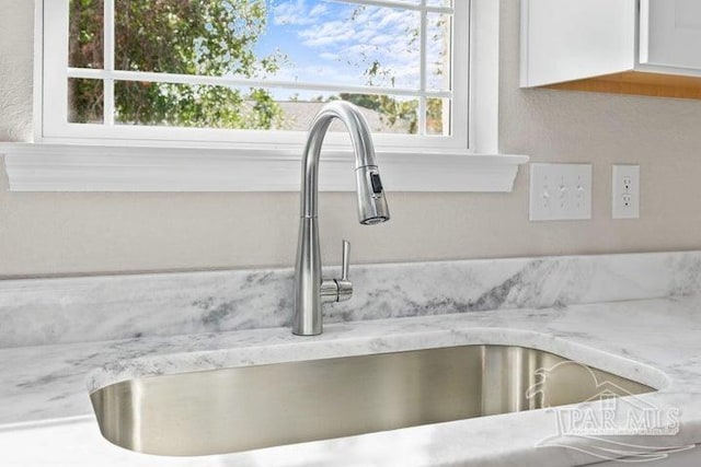 room details with light stone counters, white cabinetry, and sink