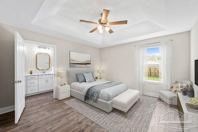 bedroom with hardwood / wood-style flooring, ceiling fan, a raised ceiling, and ensuite bath