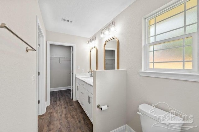 bathroom with a textured ceiling, vanity, hardwood / wood-style flooring, and toilet