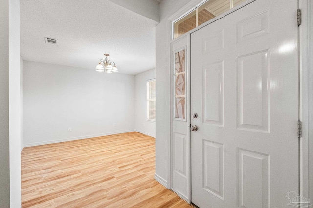 6240 Tributary St, Pensacola, FL 32526 - foyer with hardwood / wood-style flooring, a textured ceiling, and a chandelier