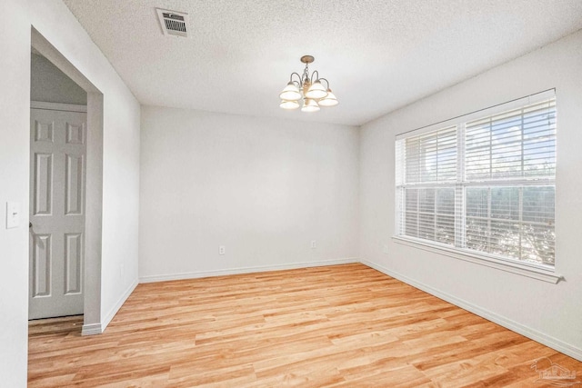 6240 Tributary St, Pensacola, FL 32526 - spare room featuring light hardwood / wood-style floors, a textured ceiling, and a notable chandelier