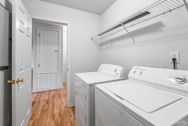 6240 Tributary St, Pensacola, FL 32526 - laundry room with a textured ceiling, light hardwood / wood-style flooring, and washing machine and clothes dryer