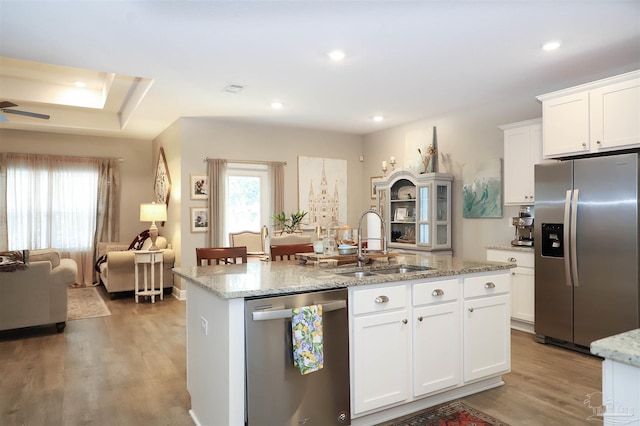 kitchen featuring sink, white cabinetry, stainless steel appliances, and an island with sink