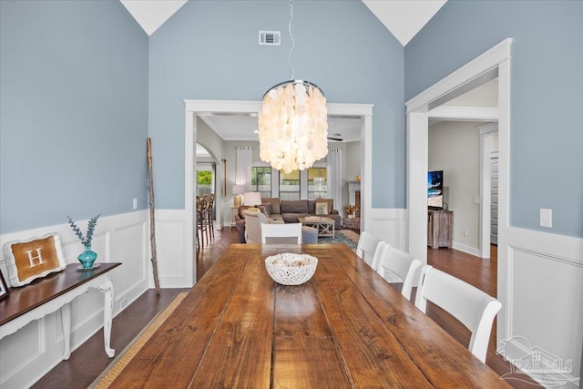 1504 Cadence Loop, Cantonment, FL 32533 - dining room featuring a chandelier, a wainscoted wall, wood finished floors, a decorative wall, and high vaulted ceiling