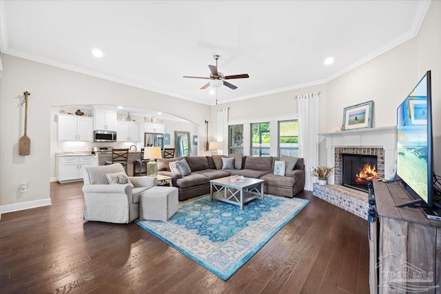 1504 Cadence Loop, Cantonment, FL 32533 - living room with arched walkways, a ceiling fan, a brick fireplace, dark wood-style floors, and baseboards