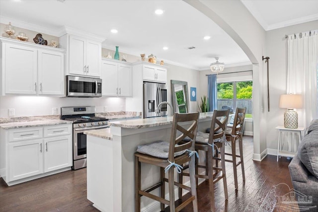 1504 Cadence Loop, Cantonment, FL 32533 - kitchen with appliances with stainless steel finishes, arched walkways, dark wood-type flooring, white cabinetry, and a center island with sink
