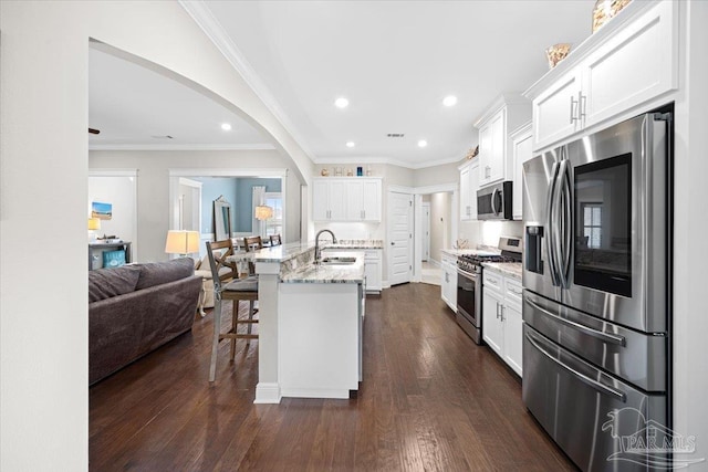1504 Cadence Loop, Cantonment, FL 32533 - kitchen featuring appliances with stainless steel finishes, a kitchen bar, white cabinets, open floor plan, and light stone countertops