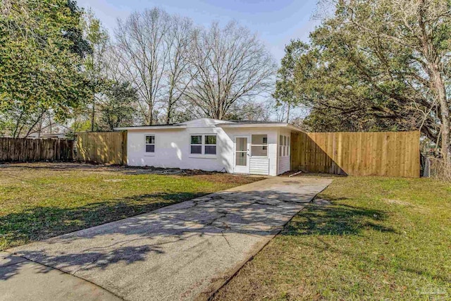 view of front of house with fence, a front lawn, concrete driveway, and stucco siding