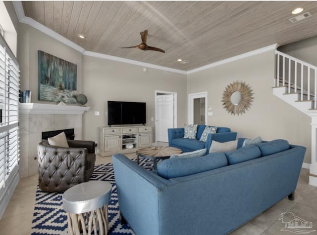 living room with a tiled fireplace, light tile patterned floors, ceiling fan, crown molding, and wooden ceiling