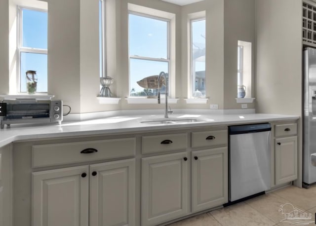 kitchen with light tile patterned floors, appliances with stainless steel finishes, sink, and white cabinets