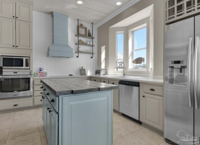 kitchen featuring white cabinetry, stainless steel appliances, a center island, tasteful backsplash, and custom exhaust hood