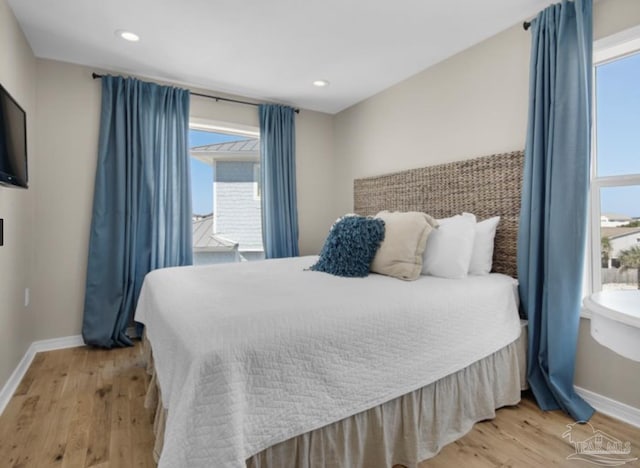 bedroom with light hardwood / wood-style floors and multiple windows