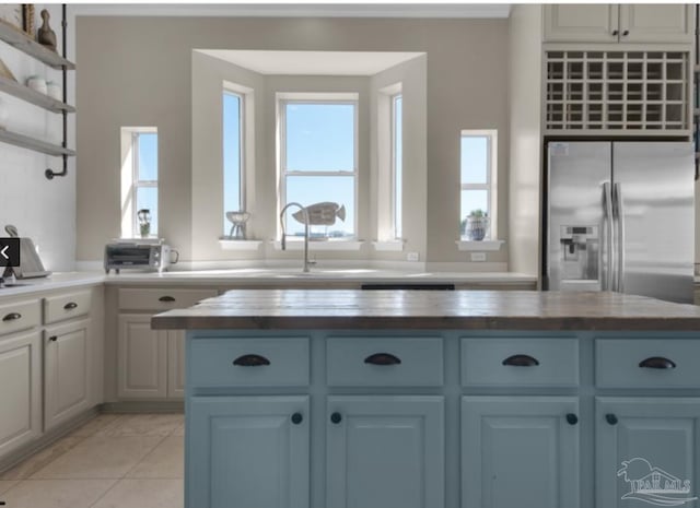 kitchen featuring wooden counters, sink, stainless steel fridge with ice dispenser, and light tile patterned floors