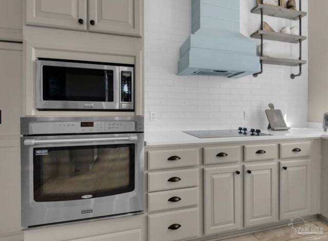 kitchen with premium range hood, appliances with stainless steel finishes, white cabinets, and decorative backsplash