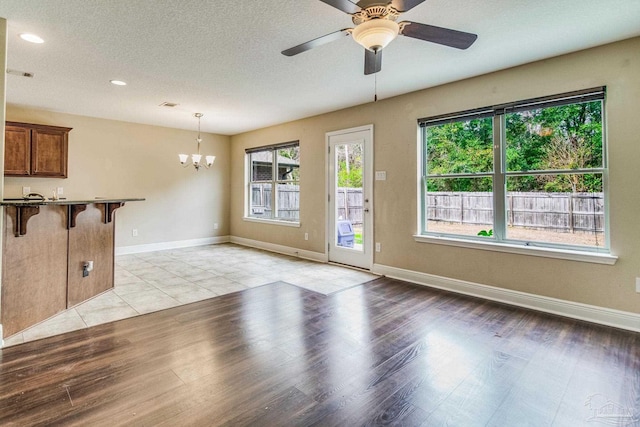 interior space featuring ceiling fan with notable chandelier, a textured ceiling, and light hardwood / wood-style flooring