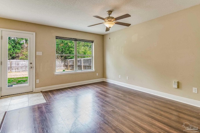 empty room featuring dark hardwood / wood-style flooring, ceiling fan, and a textured ceiling