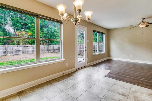 entryway featuring light tile patterned floors, ceiling fan with notable chandelier, and a wealth of natural light