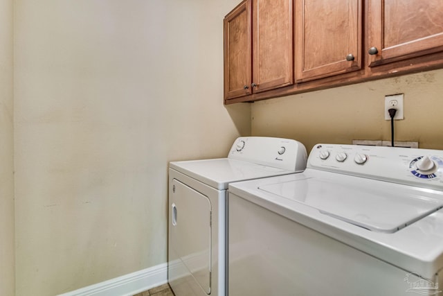 clothes washing area with cabinets and separate washer and dryer