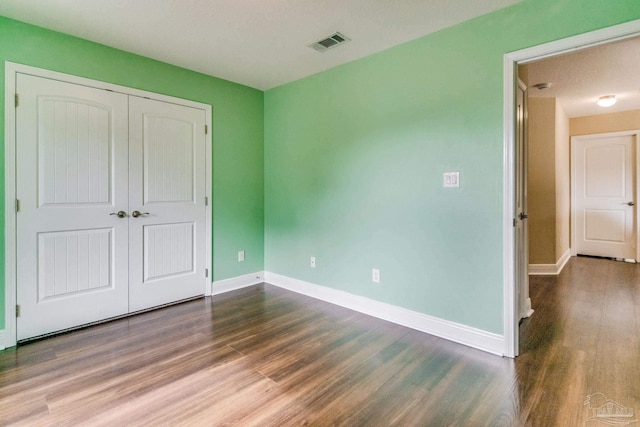 unfurnished bedroom with dark hardwood / wood-style floors and a closet