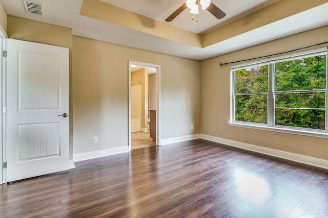 unfurnished room with dark wood-type flooring, ceiling fan, and a raised ceiling