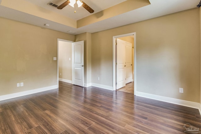 empty room featuring ceiling fan, dark hardwood / wood-style flooring, and a raised ceiling