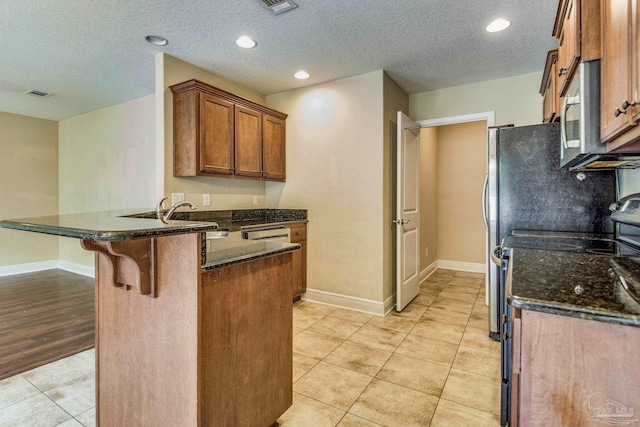 kitchen featuring sink, light tile patterned floors, a breakfast bar, range with electric stovetop, and kitchen peninsula