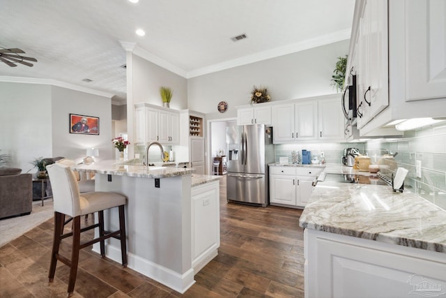 1328 Tour Dr, Gulf Breeze, FL 32563 - kitchen featuring stainless steel appliances, a peninsula, ornamental molding, a breakfast bar area, and light stone countertops